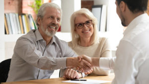 Happy-couple-shaking-hands-with-insurance-broker